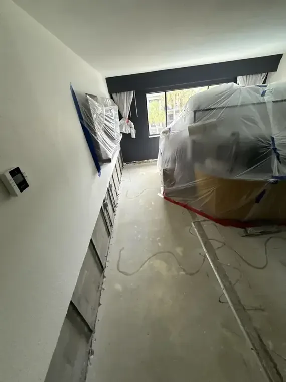 Plastic containment and a flood cut along a hallway wall during drying