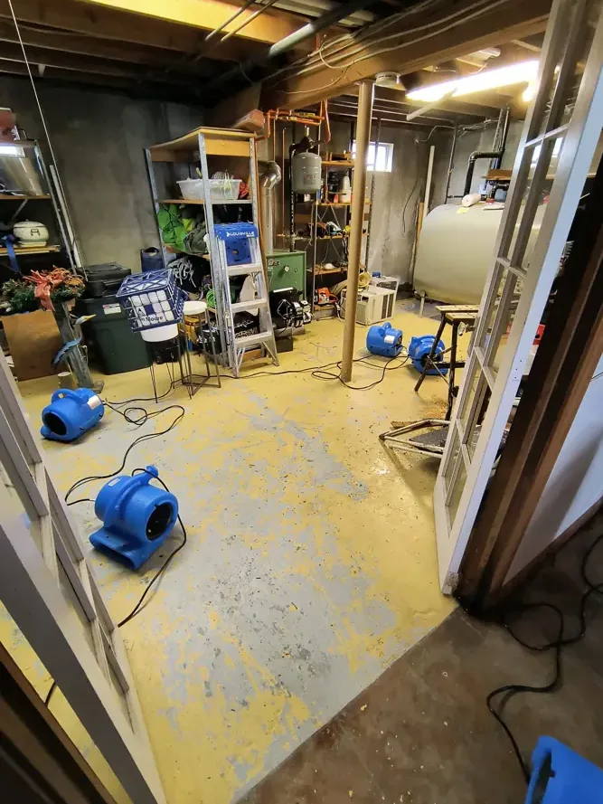 Air movers drying a wet basement workshop floor