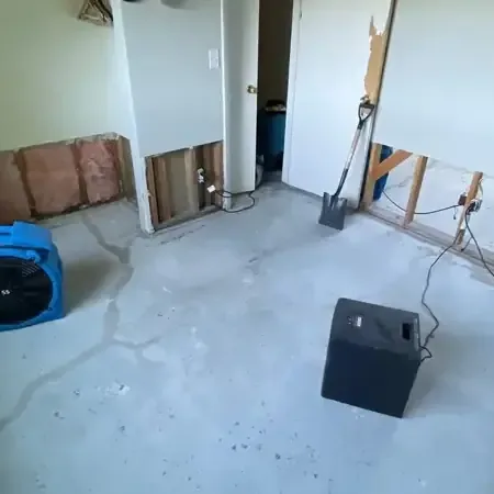 Air movers and a dehumidifier drying a room with an opened wall