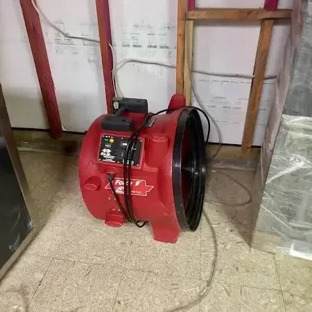 Drying equipment set up in a gutted room with wet drywall cut away