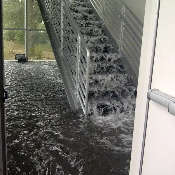 Water pouring down an indoor staircase from a burst supply pipe