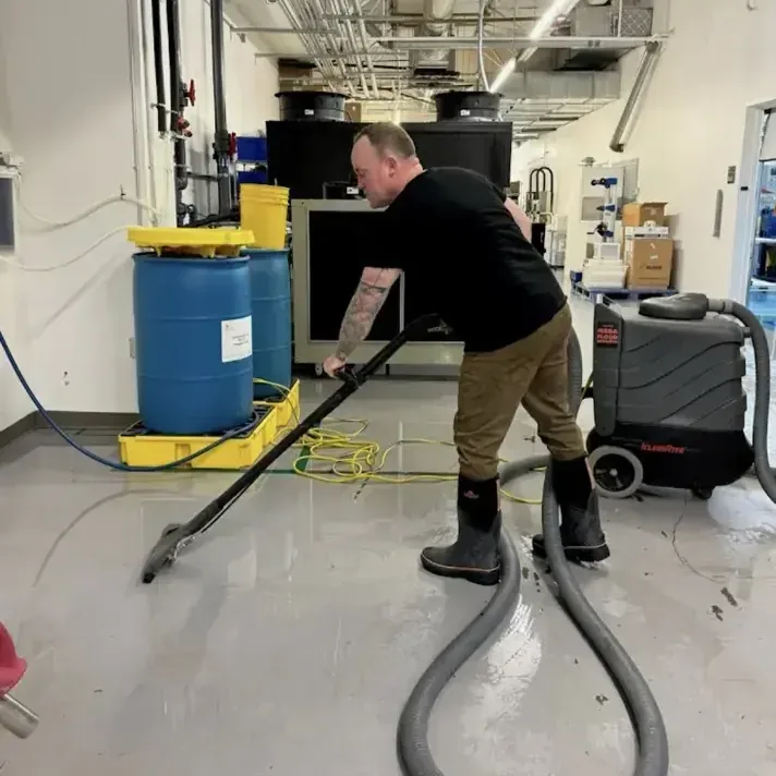 Technician extracting water from a commercial lab floor with a dehumidifier running