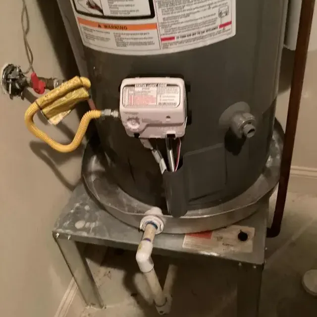 Tank water heater on a stand above a water-stained floor after a leak